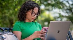 Student checking their phone and with their laptop open.